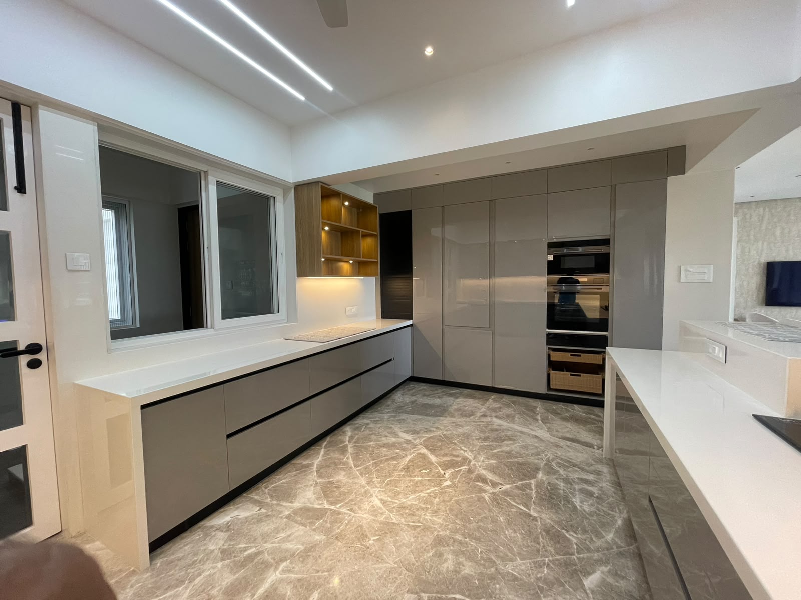 Straight-line modular kitchen in Aurangabad with handleless mocha shutters and built-in chimney by More Than Kitchen